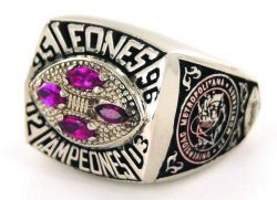 A silver ring with four red gemstones in the center, featuring the text "LEONES" on one side, "CAMPEONES" on the other, and additional detailed engravings.