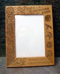 A wooden picture frame with "Seniors 2006" and "World's Greatest Grandparents" engraved on it, along with illustrations of stars, birds, flowers, and masks.